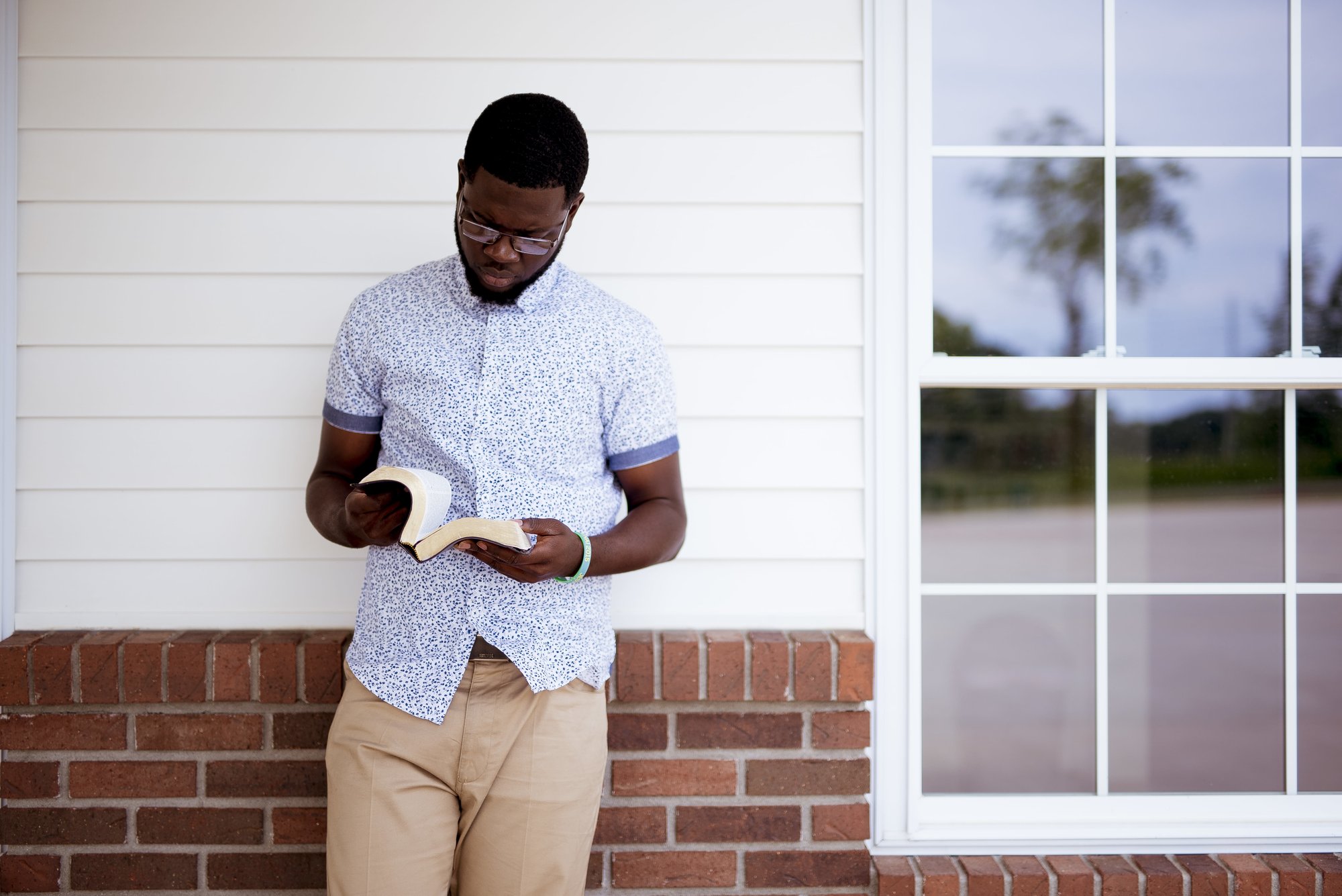 male-leaning-against-wall-while-reading-bible male-leaning-against-wall-while-reading-bible